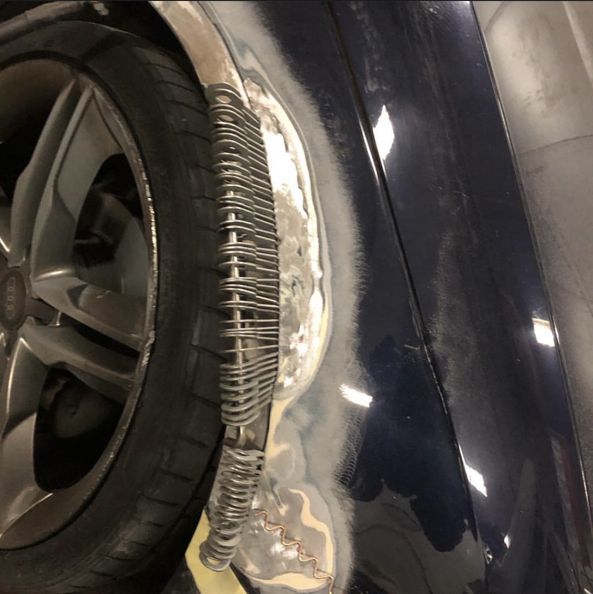 Plaatwerk aan de wielkast van een donkere auto